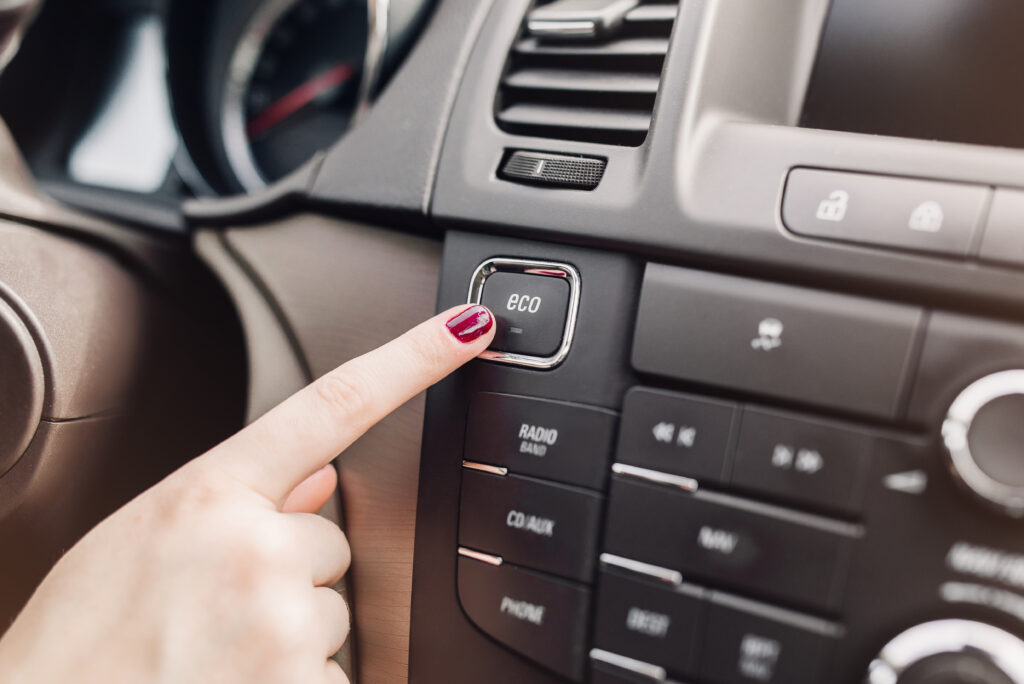 Finger pressing the eco mode on a car dashboard