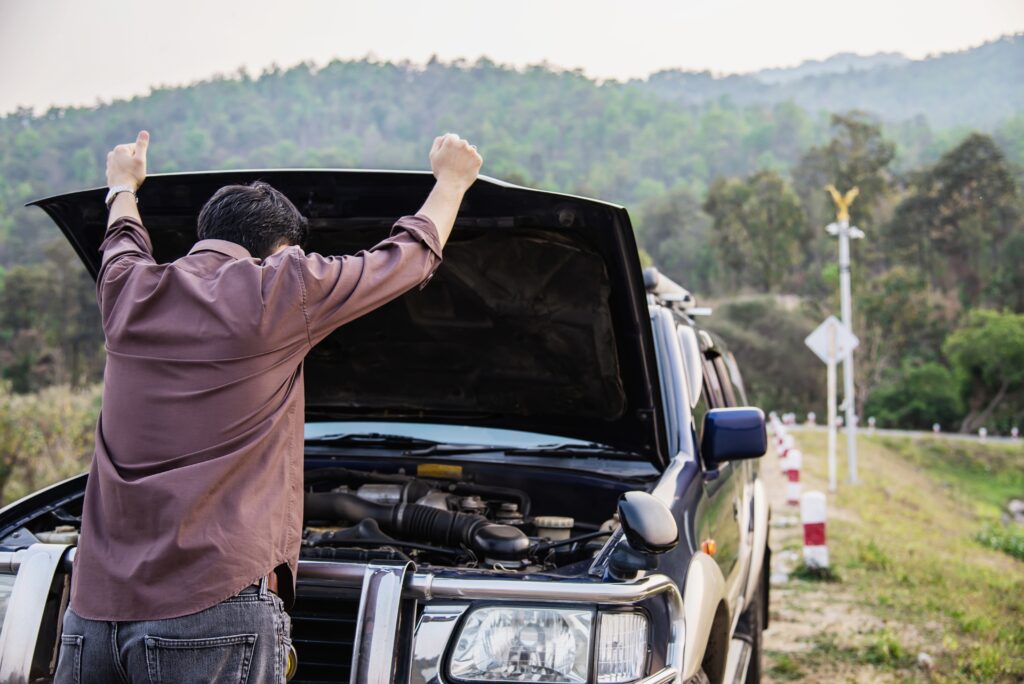 Man looking at car engine on the roadside