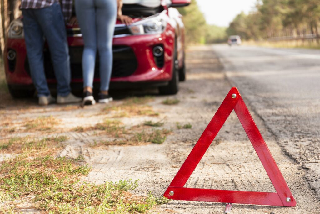 Red triangle sign on the road, car problems while traveling